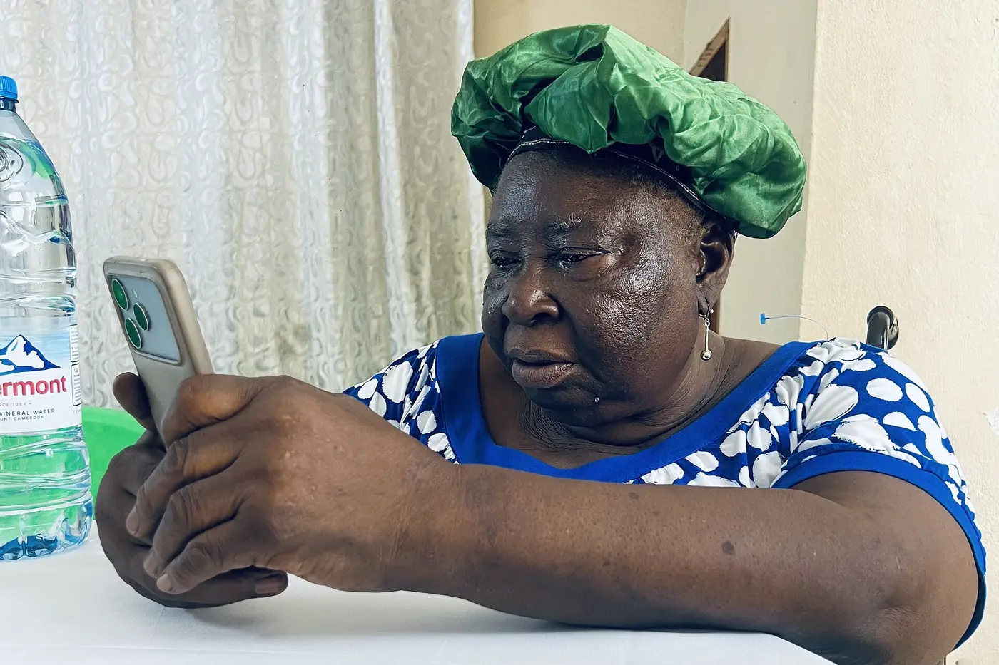 Une femme consulte son téléphone, assise à une table.